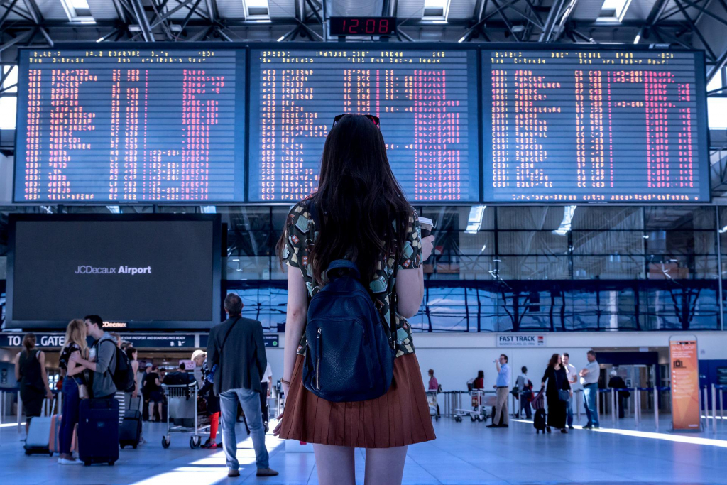 Eine junge Frau steht vor einer Flughafenanzeigetafel