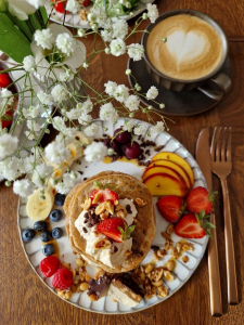 Frühstücksteller mit Pancakes, Früchten und einem Kaffee